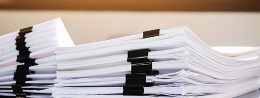 Image of stacks of documents bound with clips..